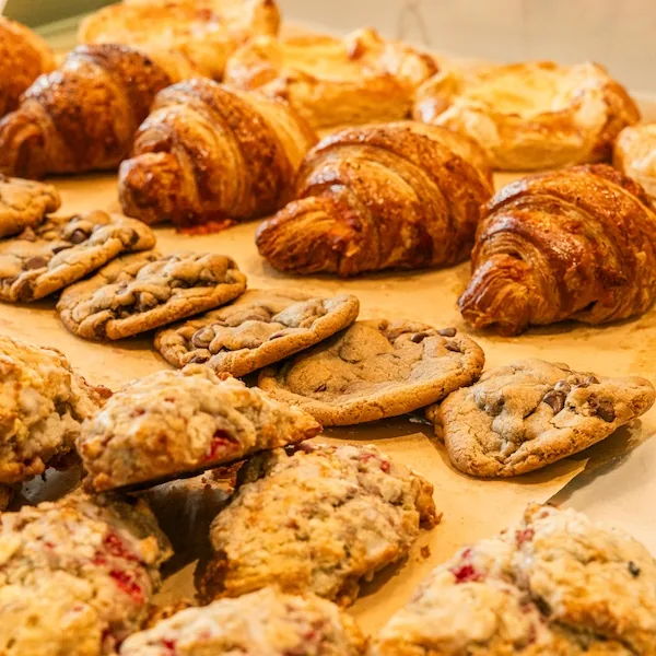 A tray of freshly baked croissants, chocolate chip cookies and berry scones