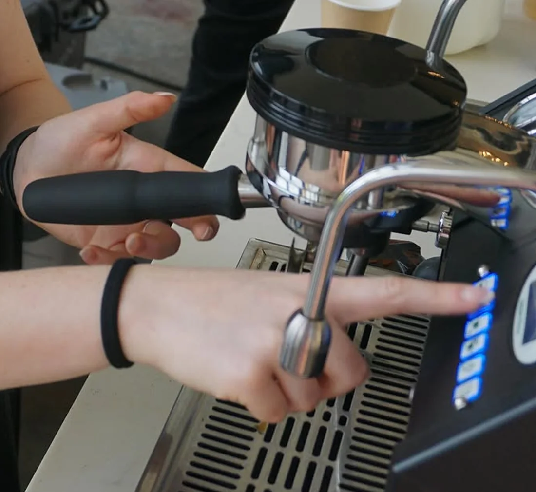 A barista's hands locking a portafilter into the espresso machine