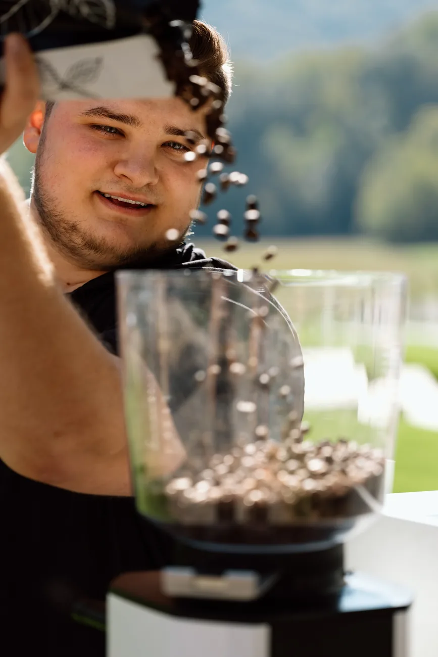 A Morning Brew Co barista at the grinder beside the cart, outdoors
