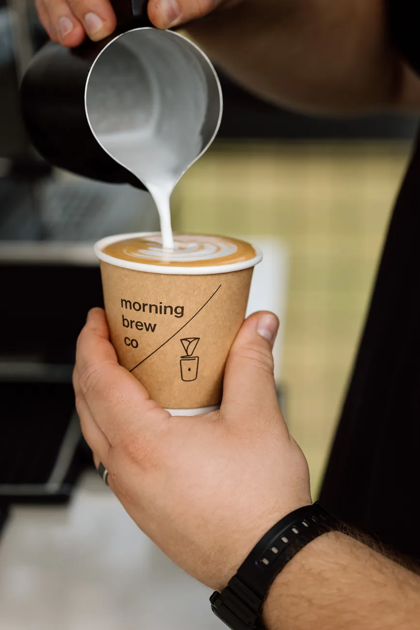 Milk poured into a Morning Brew Co branded cup, the rosetta forming