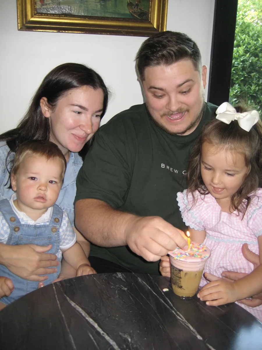 Denis and his family at a marble table in the shop, his daughter reaching for a sprinkled drink