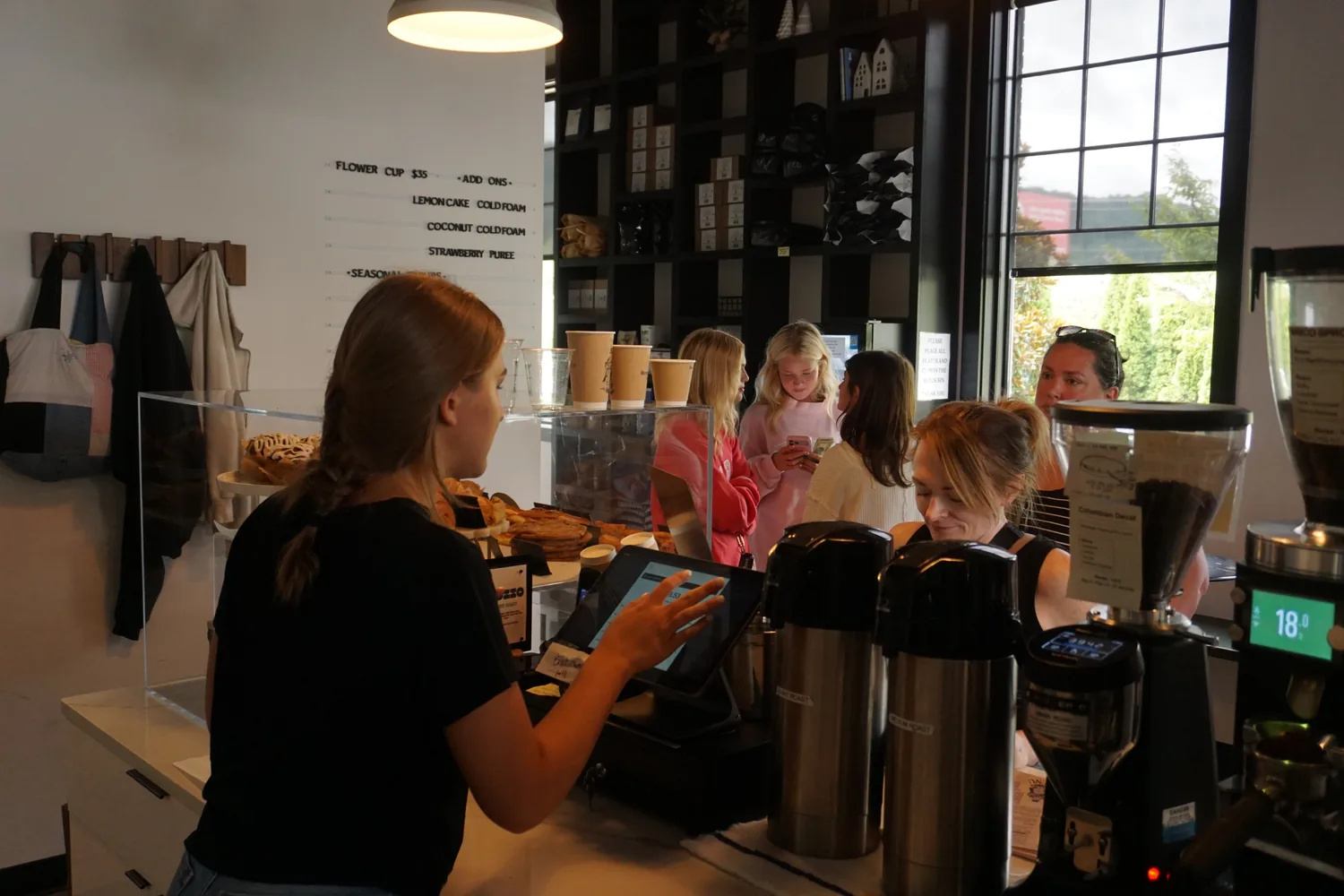 An order being taken at the counter, the pastry case full and customers waiting
