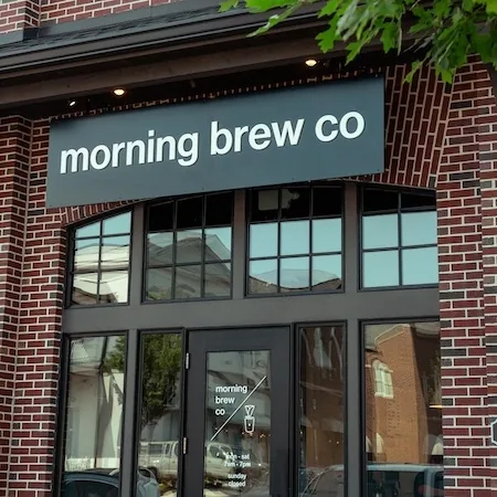 The brick storefront at Cambridge Square, with black framed windows and greenery above the door