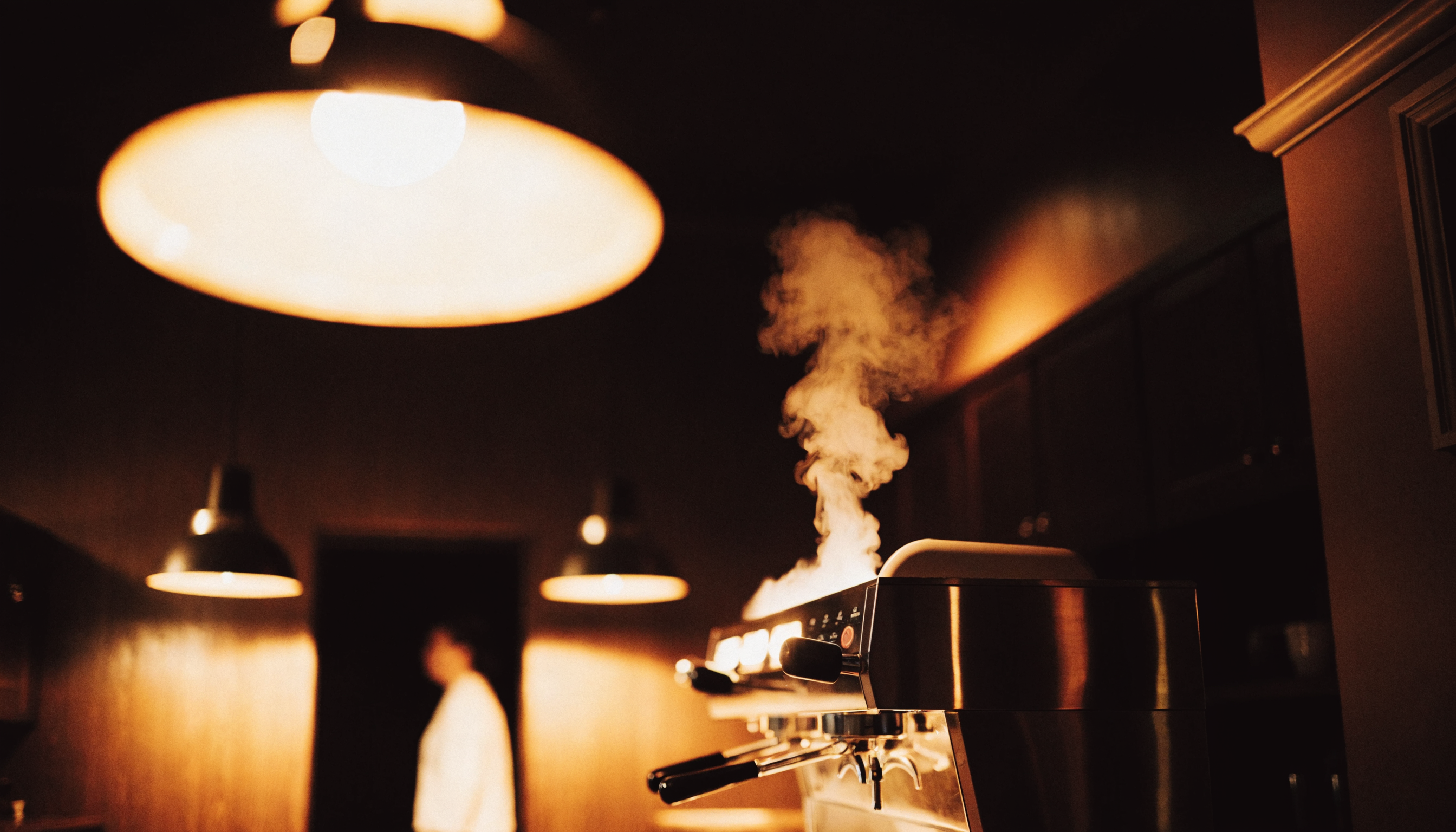 The Morning Brew Co. room at evening, gold pendant lights over the espresso machine
