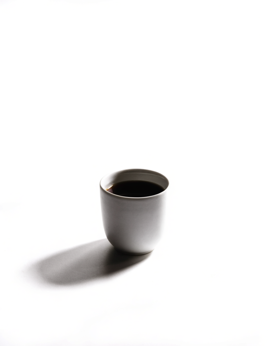 a ceramic cup of black filter coffee on a white table